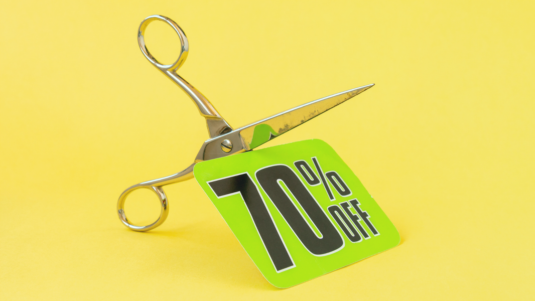 Schere schneidet ein grünes Rabattschild mit „70 % OFF“ vor gelbem Hintergrund – Symbolbild für Preisangaben und Rabatte nach der PAngV
