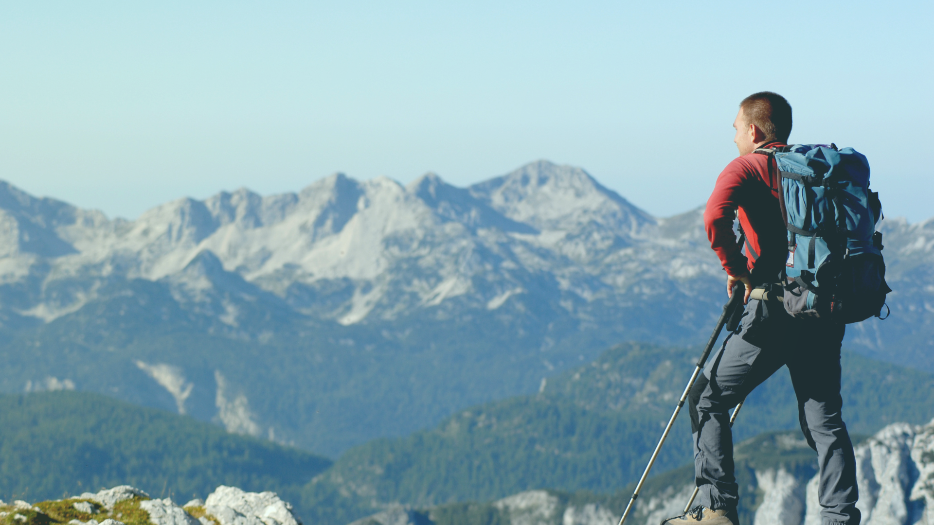 Wanderer mit Rucksack blickt auf ein Bergpanorama.