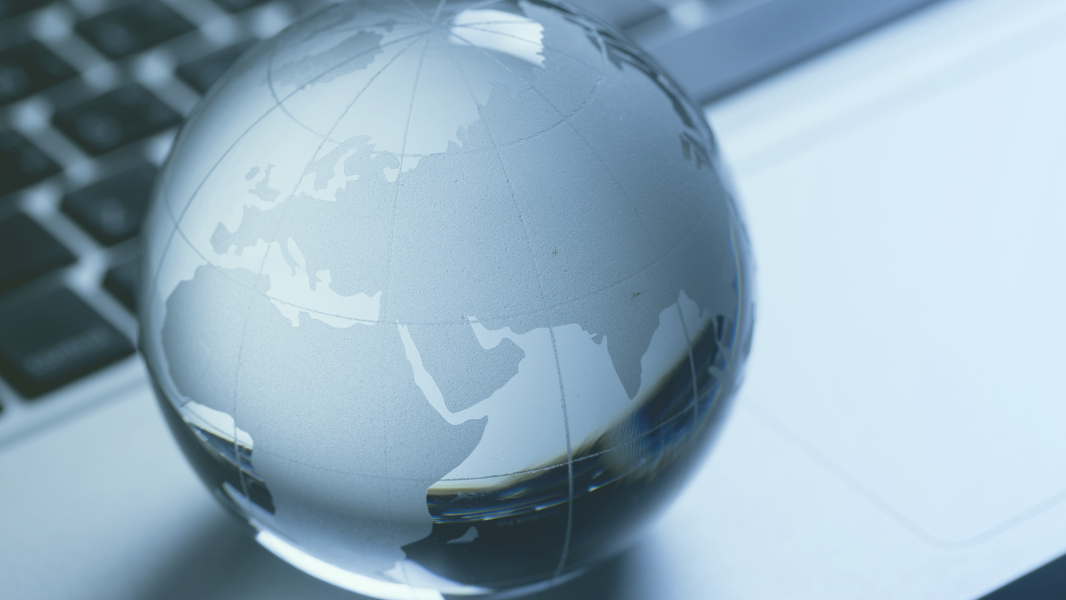 Gläserne Weltkugel auf einer Laptop Tastaur